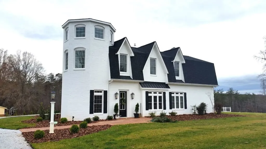 A completed white custom home with a dark roof on a landscaped property.